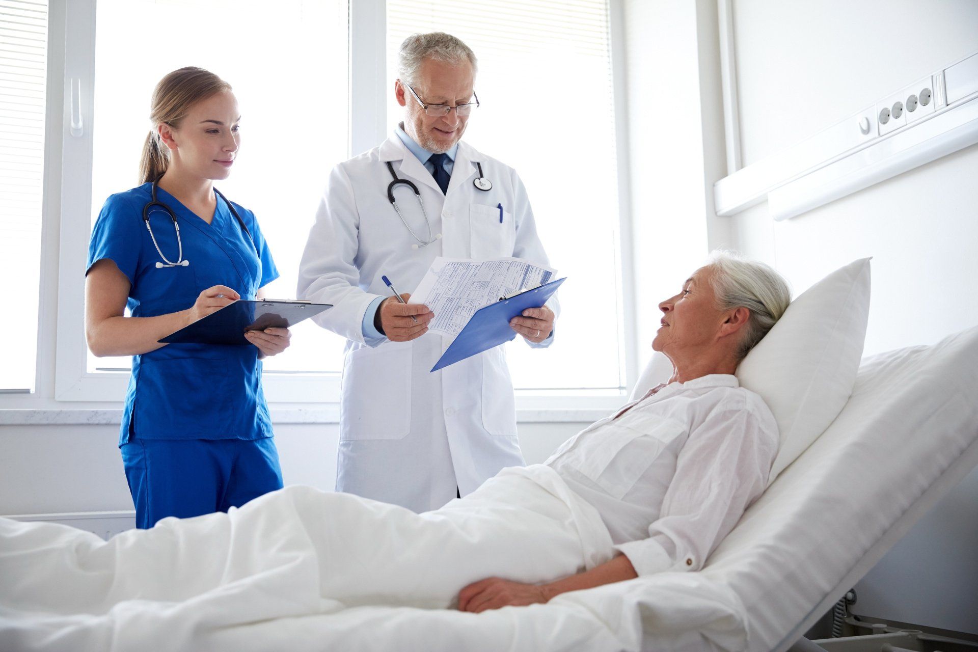 A doctor and nurse are talking to a patient in a hospital bed.
