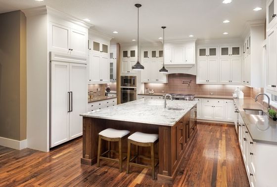 Spacious kitchen with white cabinets, a wooden island, granite countertops, and hardwood floors.