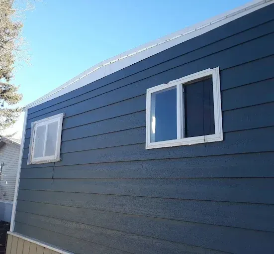 Blue house with white-framed windows against a clear blue sky.