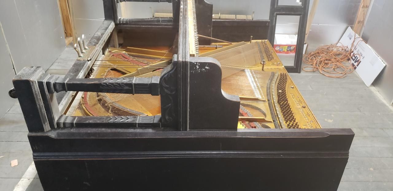 A black piano is sitting on a concrete floor in a room.