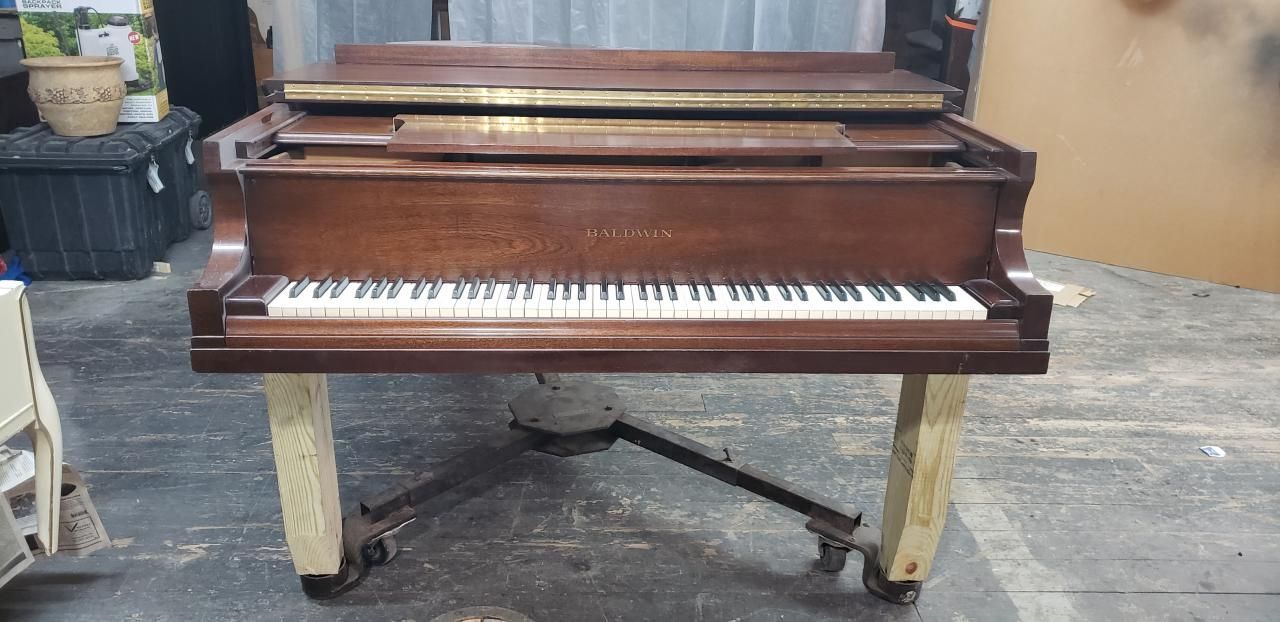 A piano is sitting on a wooden stand in a room.