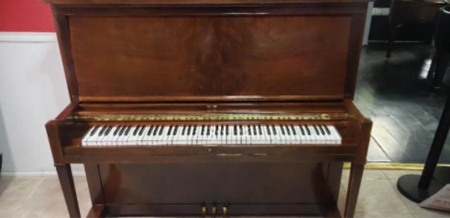 A piano is sitting on a wooden floor in a room.