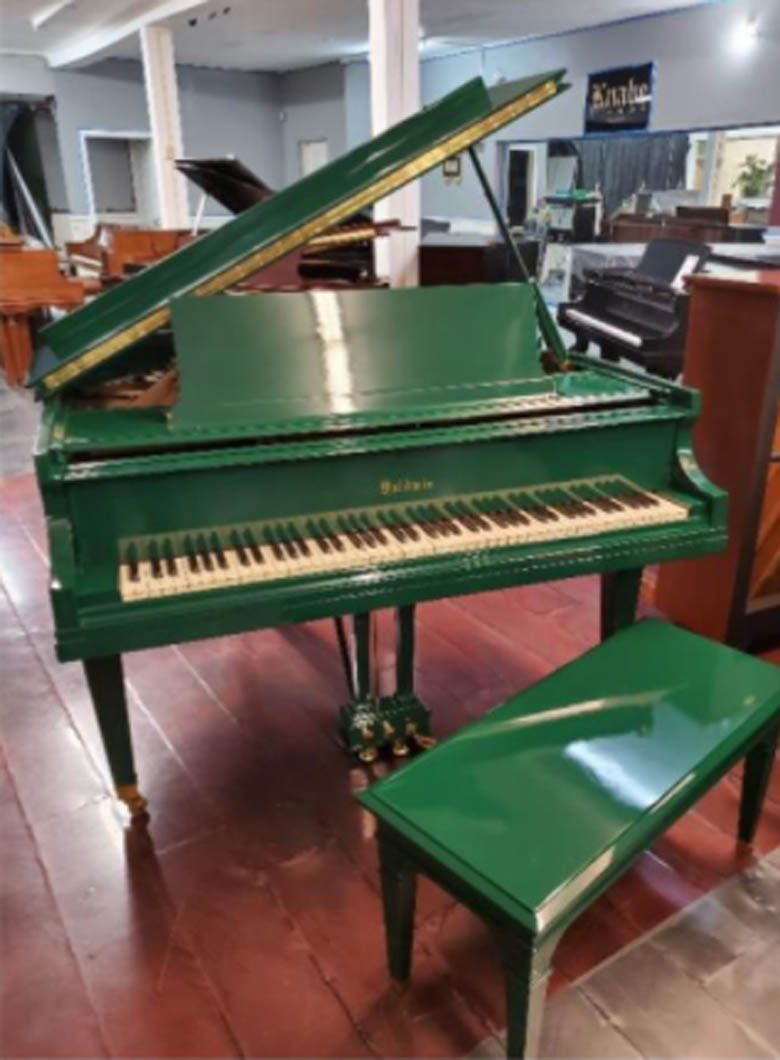 A green grand piano with a bench next to it