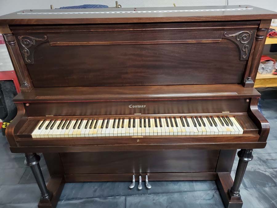 A piano is sitting on a tiled floor in a room.