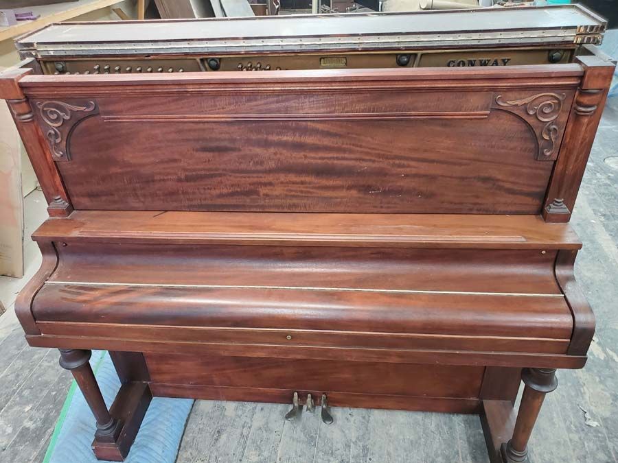 A wooden piano is sitting on a carpet in a room.