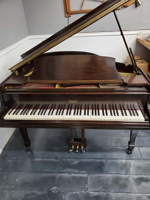 A piano is sitting on a wooden floor in a room