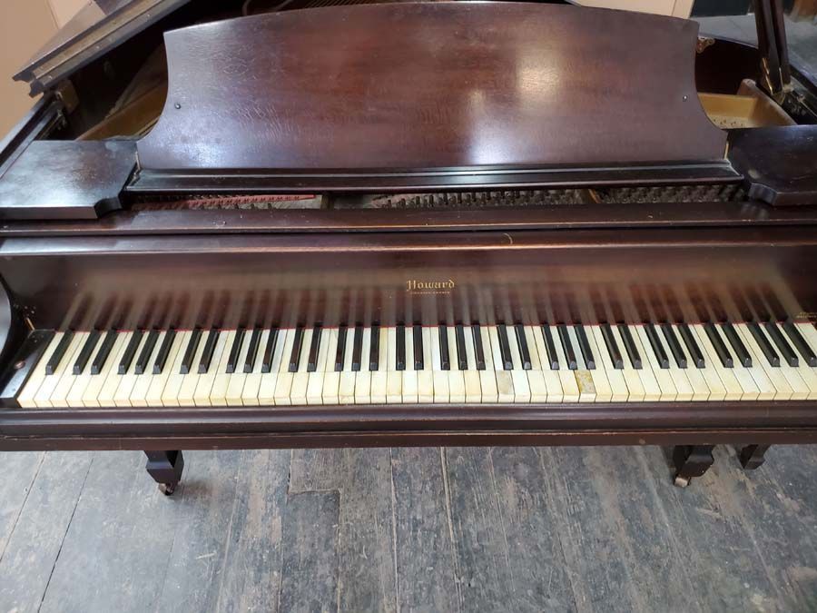 A piano is sitting on a wooden floor in a room