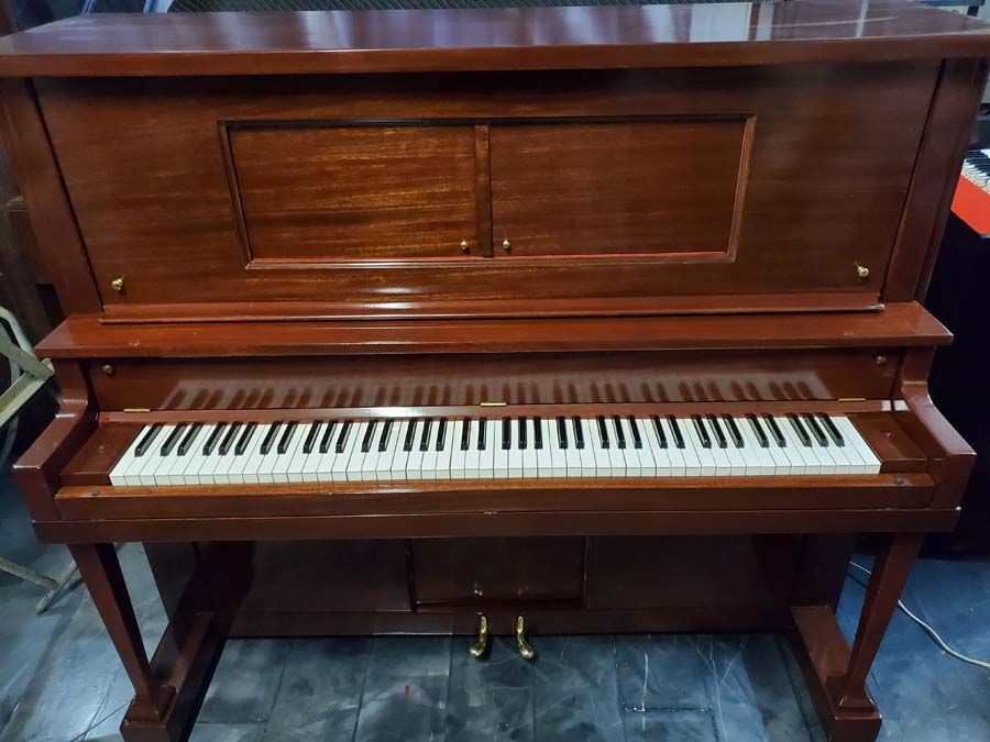 A piano is sitting on a tiled floor in a room.