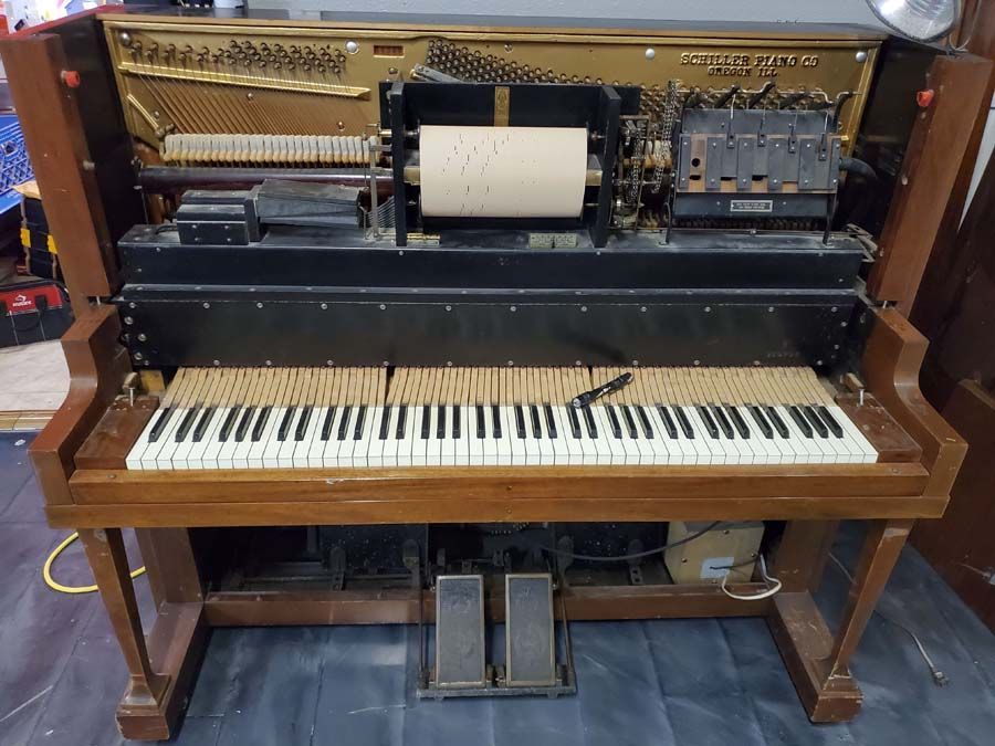 An old piano is sitting on a wooden floor in a room.