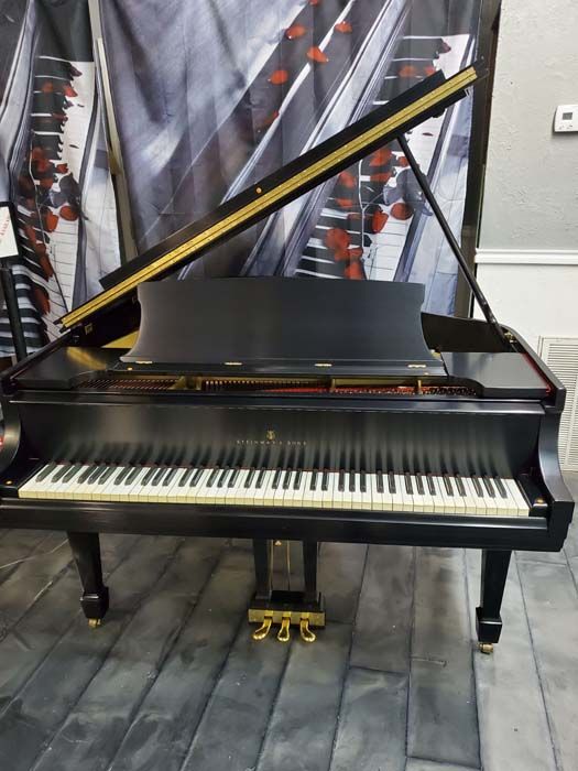 A black grand piano is sitting on a wooden floor.