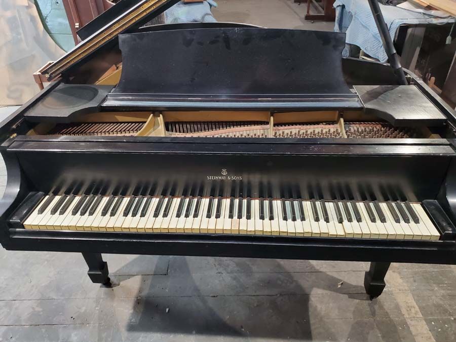 A black grand piano with white keys is sitting on the floor