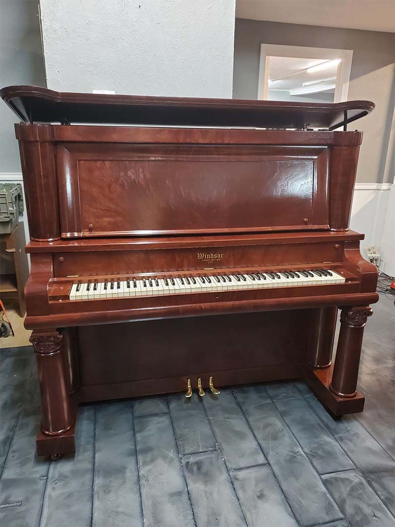 A piano is sitting on a tiled floor in a room.