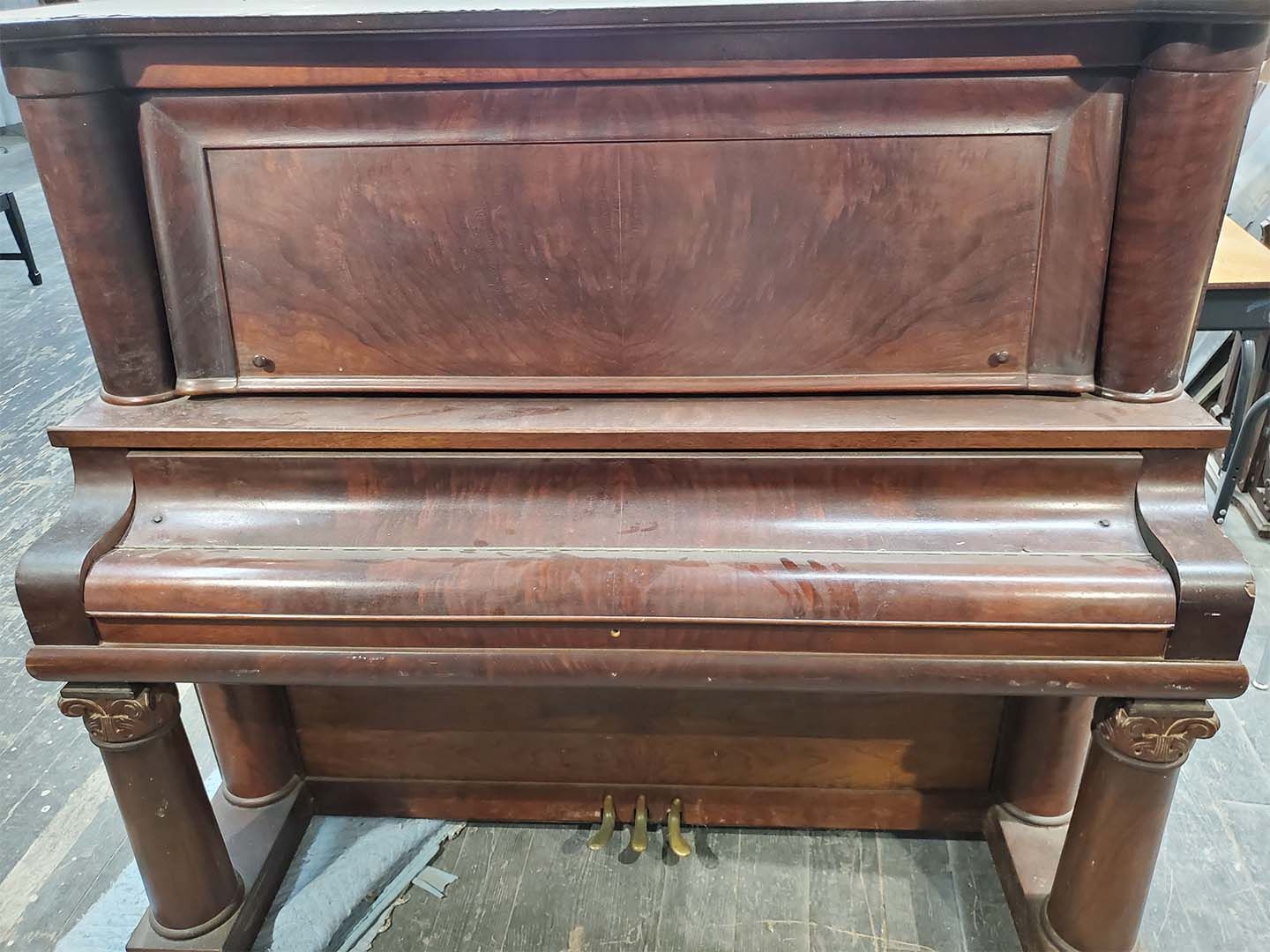 A wooden piano is sitting on a wooden floor in a room.