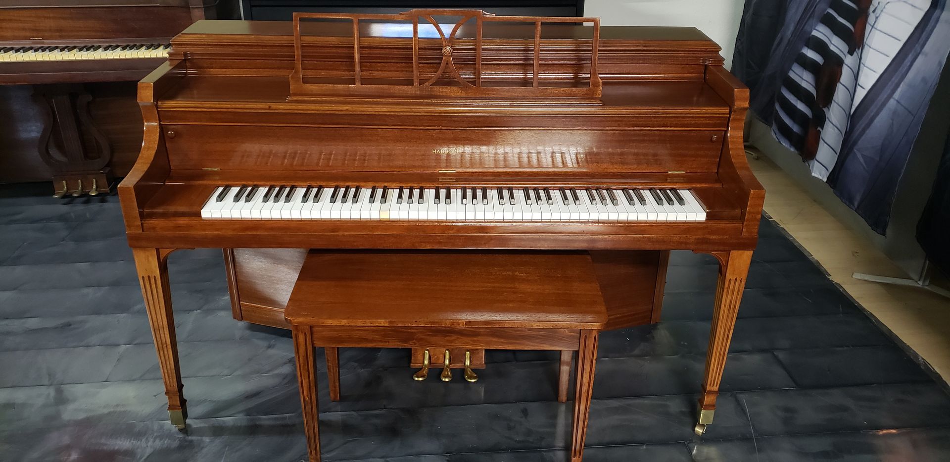 A wooden piano with a bench next to it in a room.