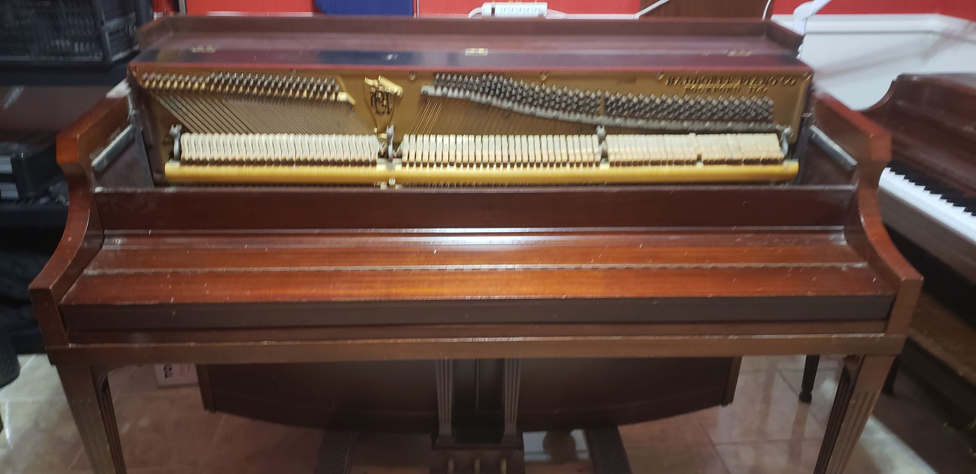 A piano is sitting on a wooden floor in a room.