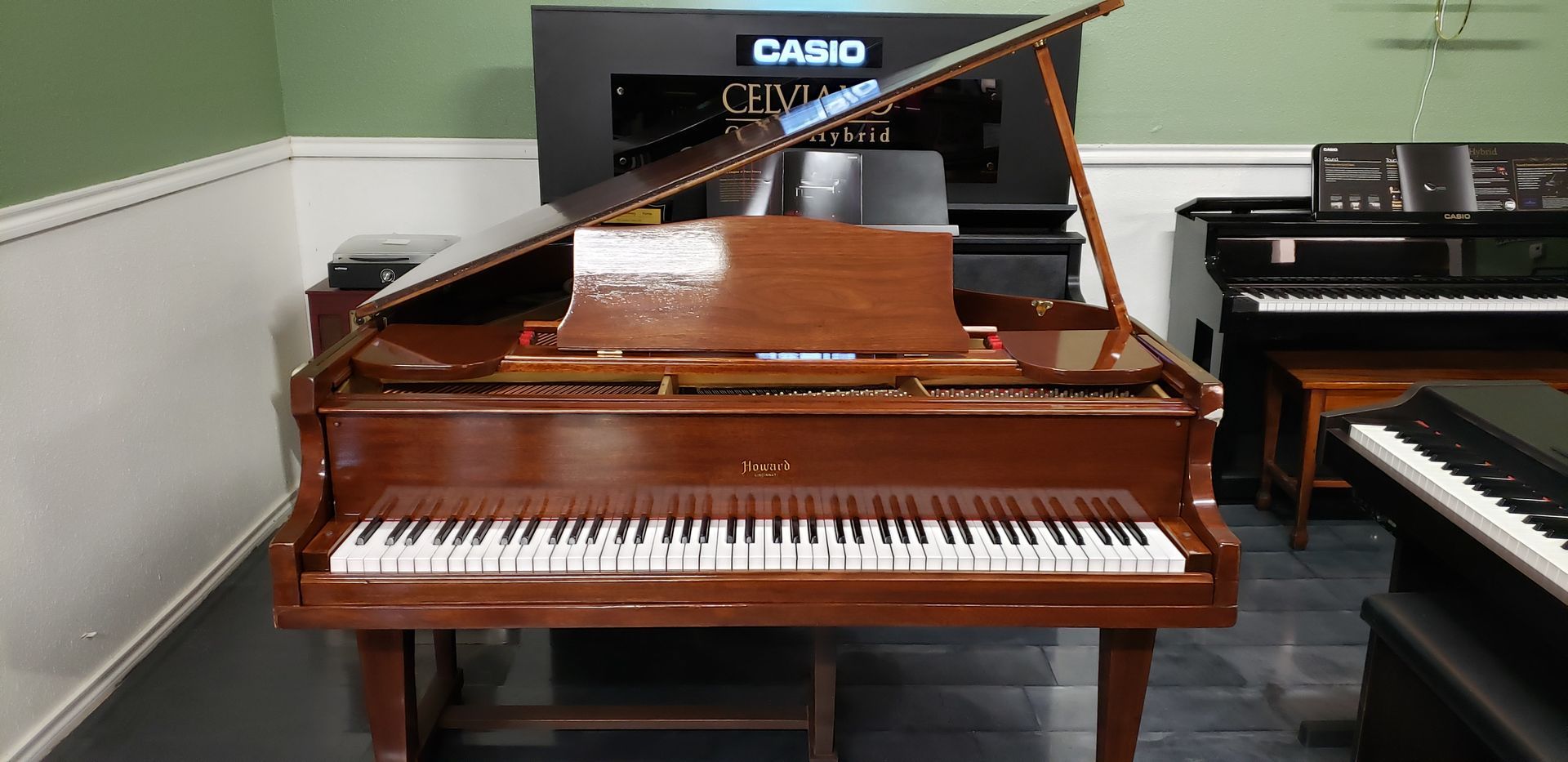 A grand piano is sitting in a room with other pianos.