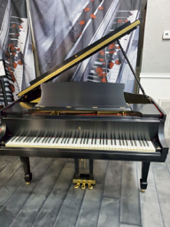 A black grand piano is sitting on a wooden floor.