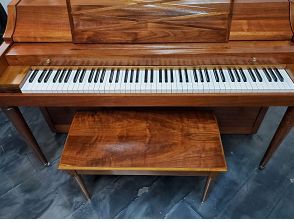 A wooden piano with a bench next to it.