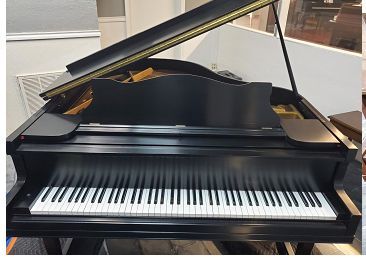 A black grand piano with the lid open is sitting on a table in a room.