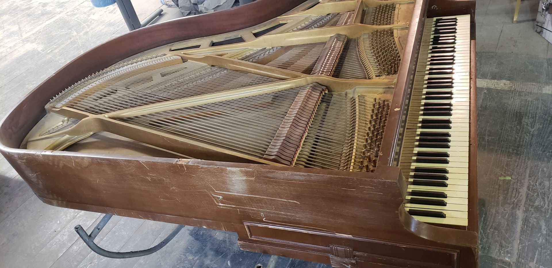 A brown grand piano is sitting on a wooden floor.