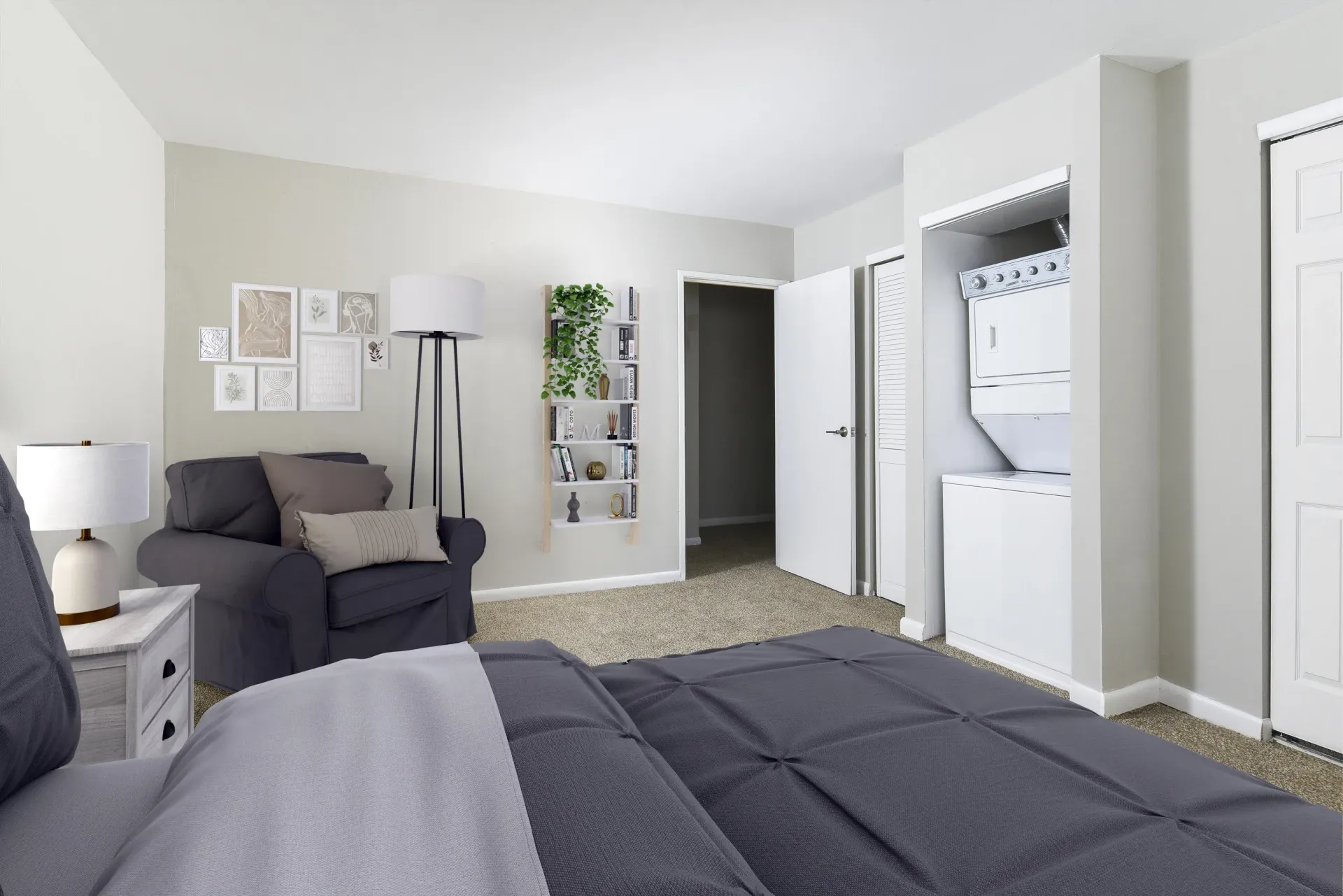 Bedroom in an apartment with a gray bedspread, seating area, and a laundry closet at Holly Court, offers apartments for rent in Pitman, NJ.
