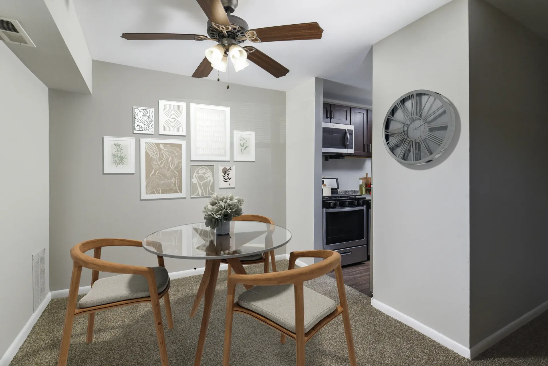 Round glass dining table with wooden chairs in a neutral-toned apartment dining area at Holly Court, offers apartments for rent in Pitman, NJ.