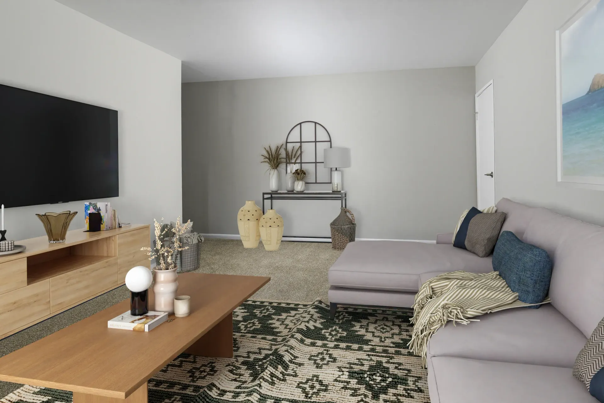 Living room in an apartment with a large TV, light wood console, and gray sectional at Holly Court, offers apartments for rent in Pitman, NJ.