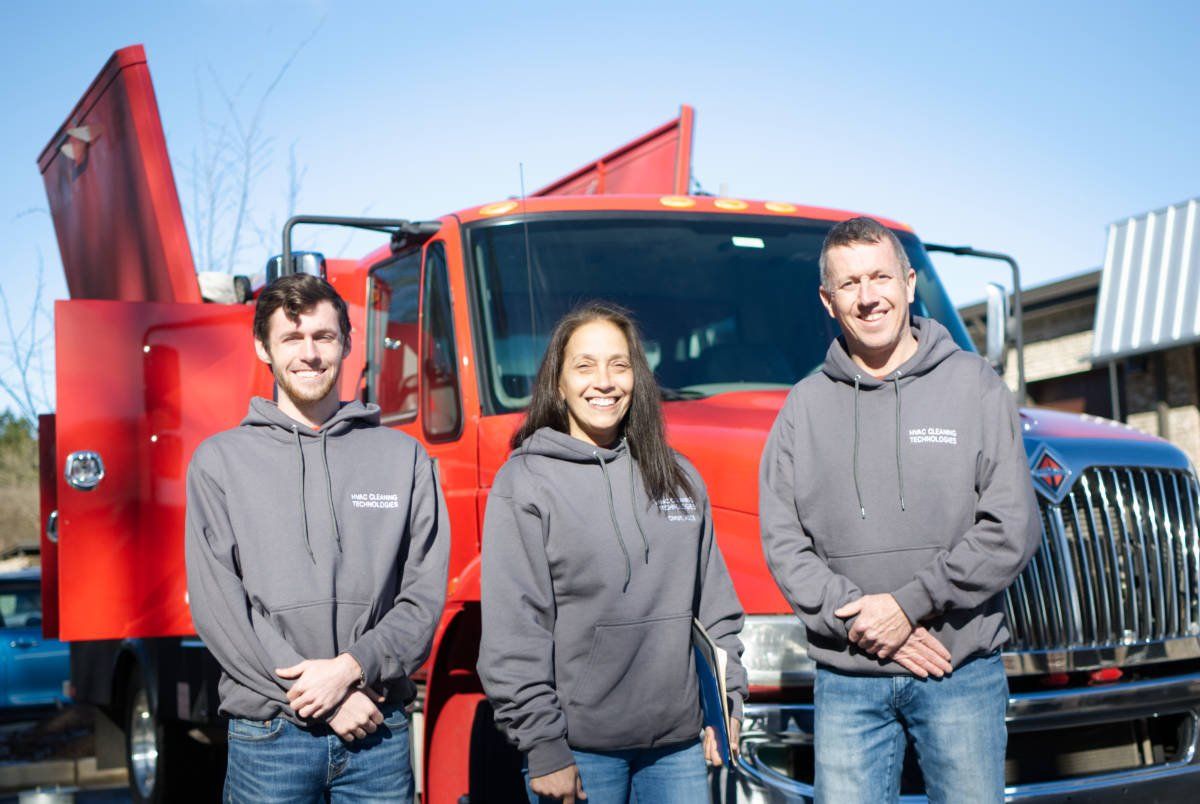 A group of people standing in front of a red truck.
