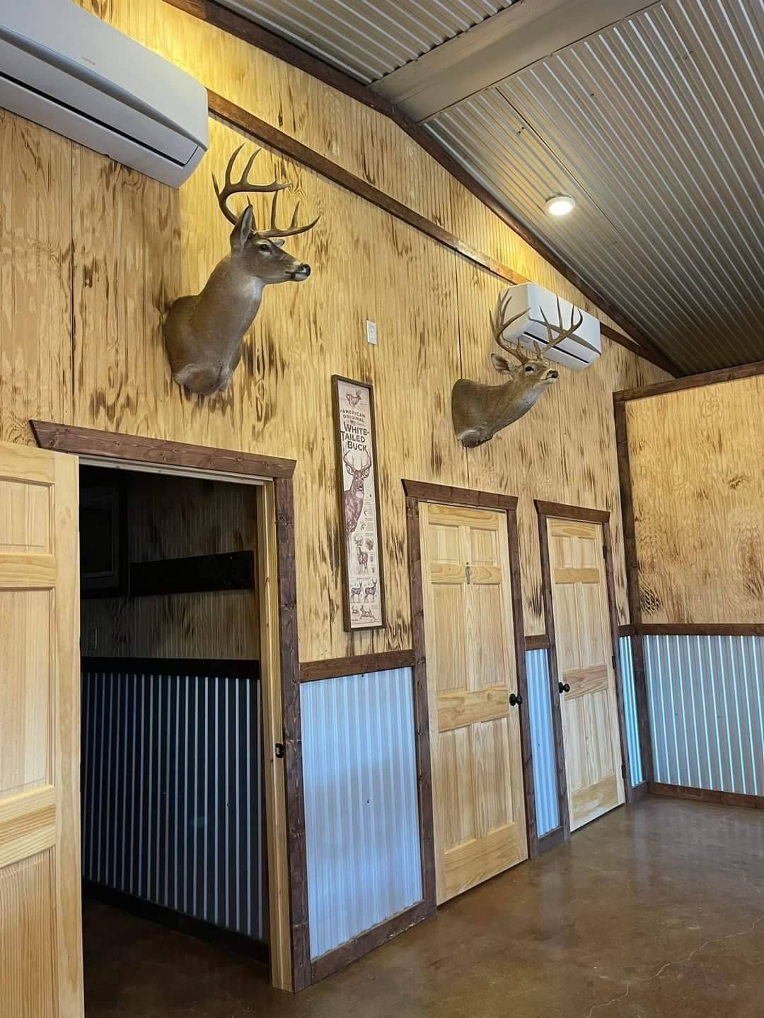 Rustic interior with taxidermied deer heads, wooden doors, and corrugated metal walls.