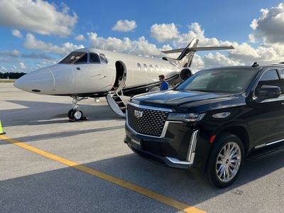 Two black cars are parked next to each other on a runway.