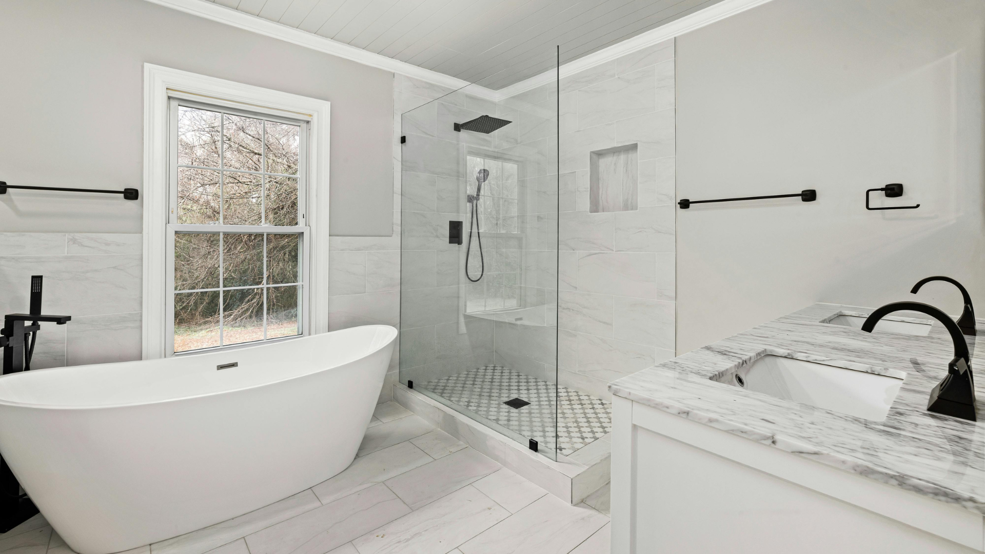 Elegant white bathroom with a freestanding tub, glass shower, and marble countertops.