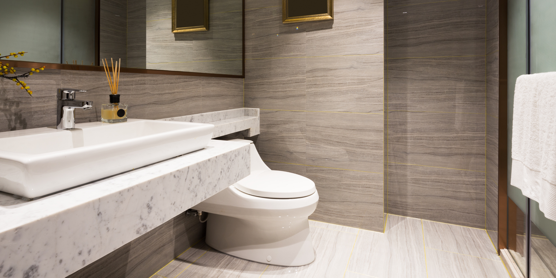 Modern bathroom with a white sink, toilet, and light gray tiled walls and floor.