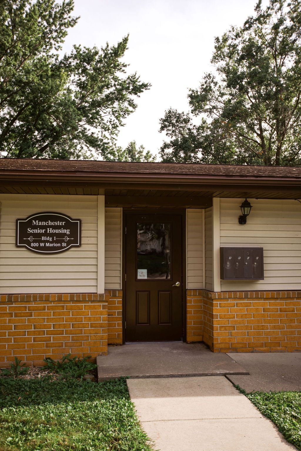 A small brick building with a sign on the front door that says ' lake court '