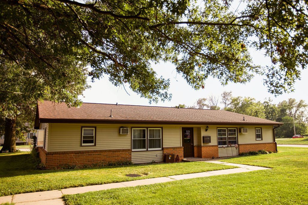 A house with a brown roof is sitting on top of a lush green field.