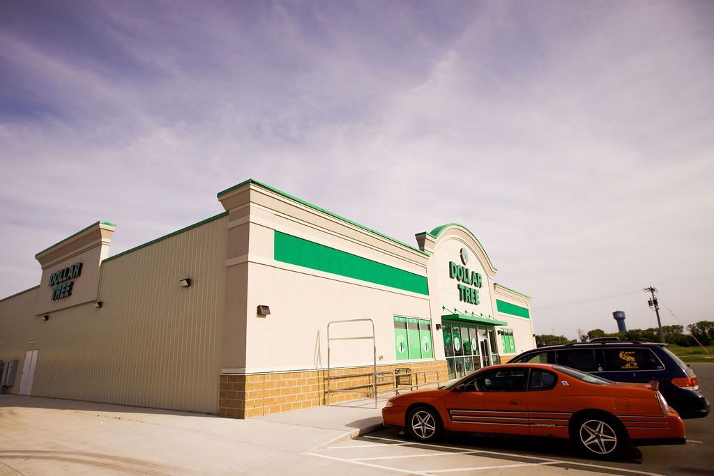 A red car is parked in front of a store.