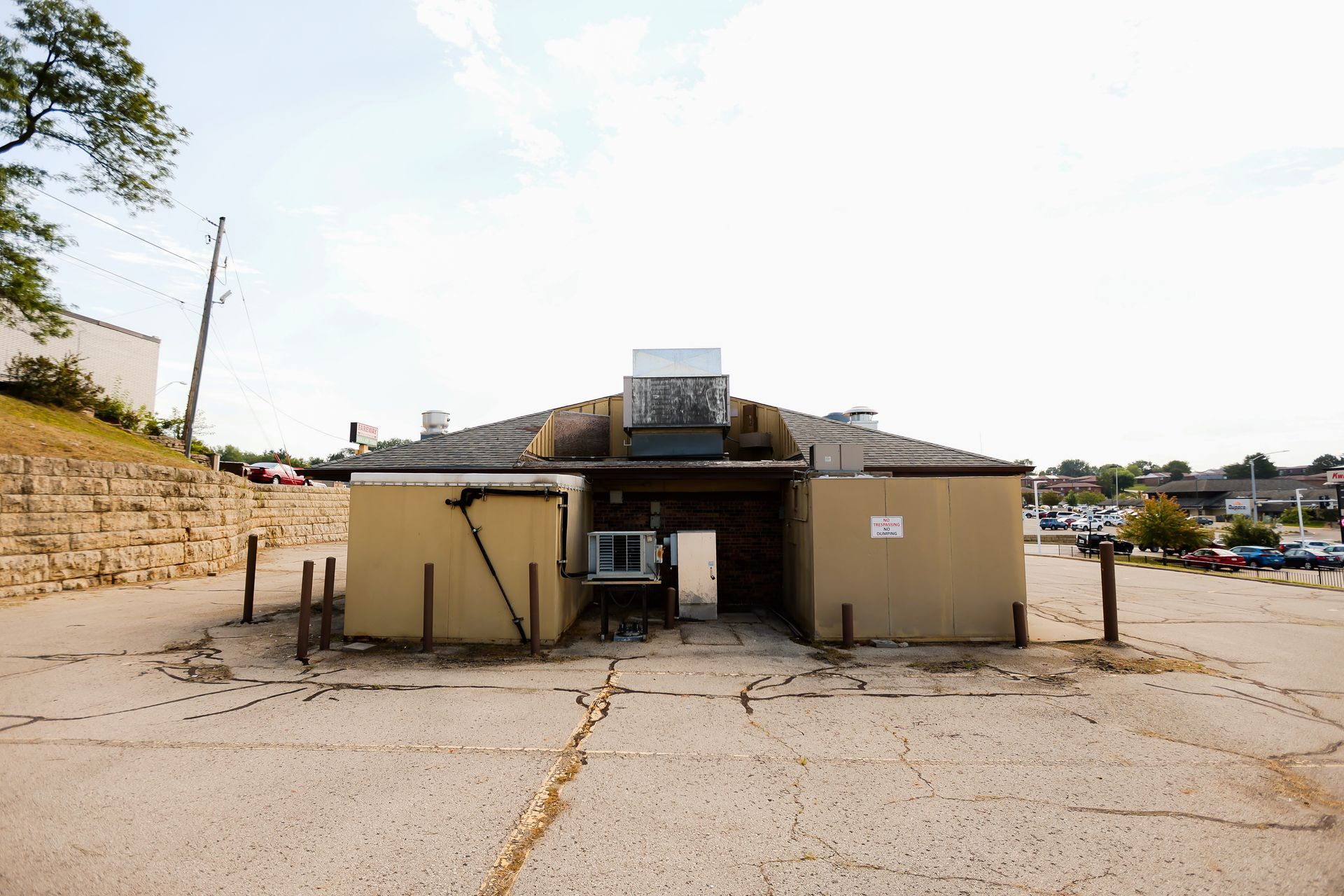 An old building is sitting in the middle of a parking lot.