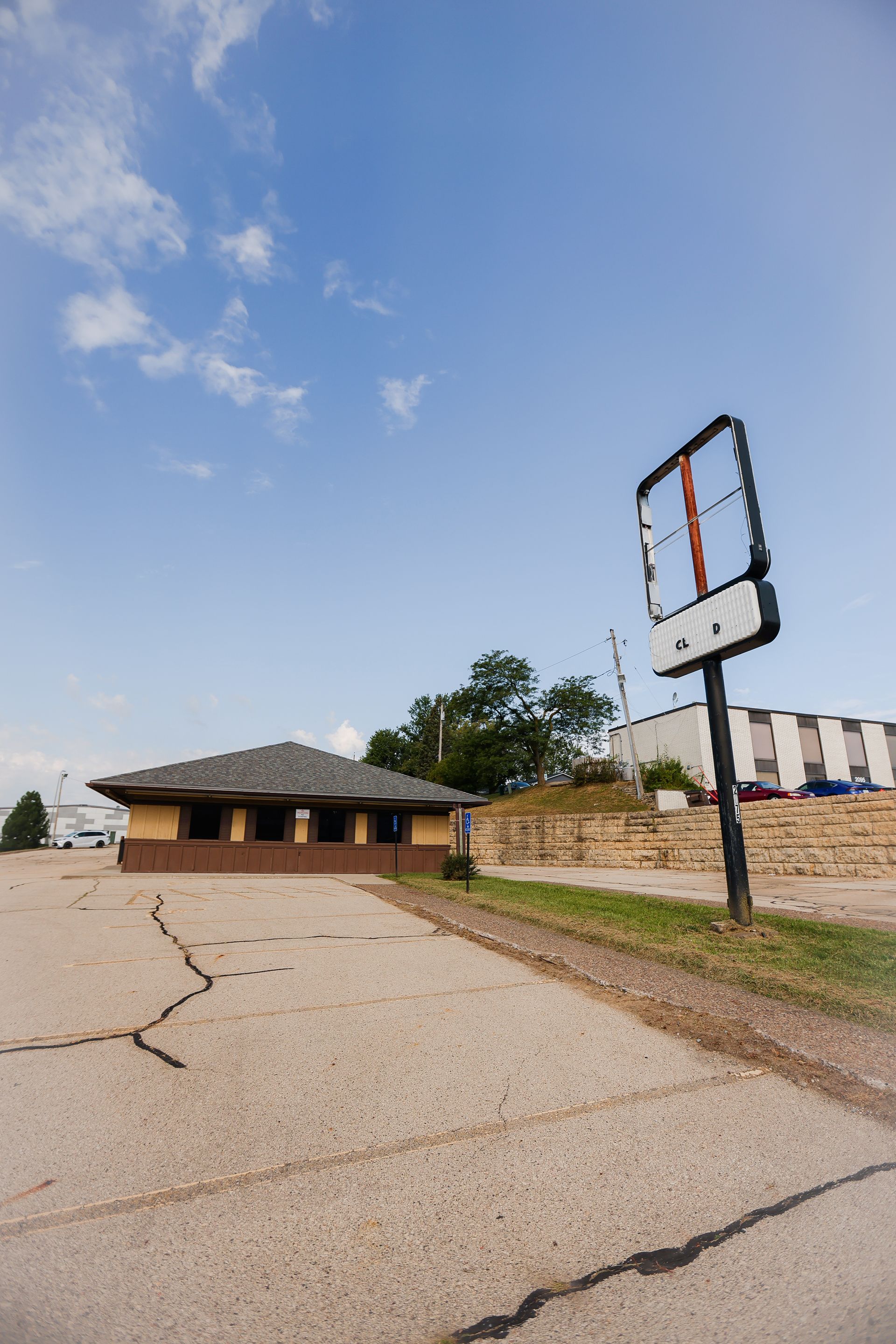 An empty parking lot with a building in the background and a billboard in the foreground.