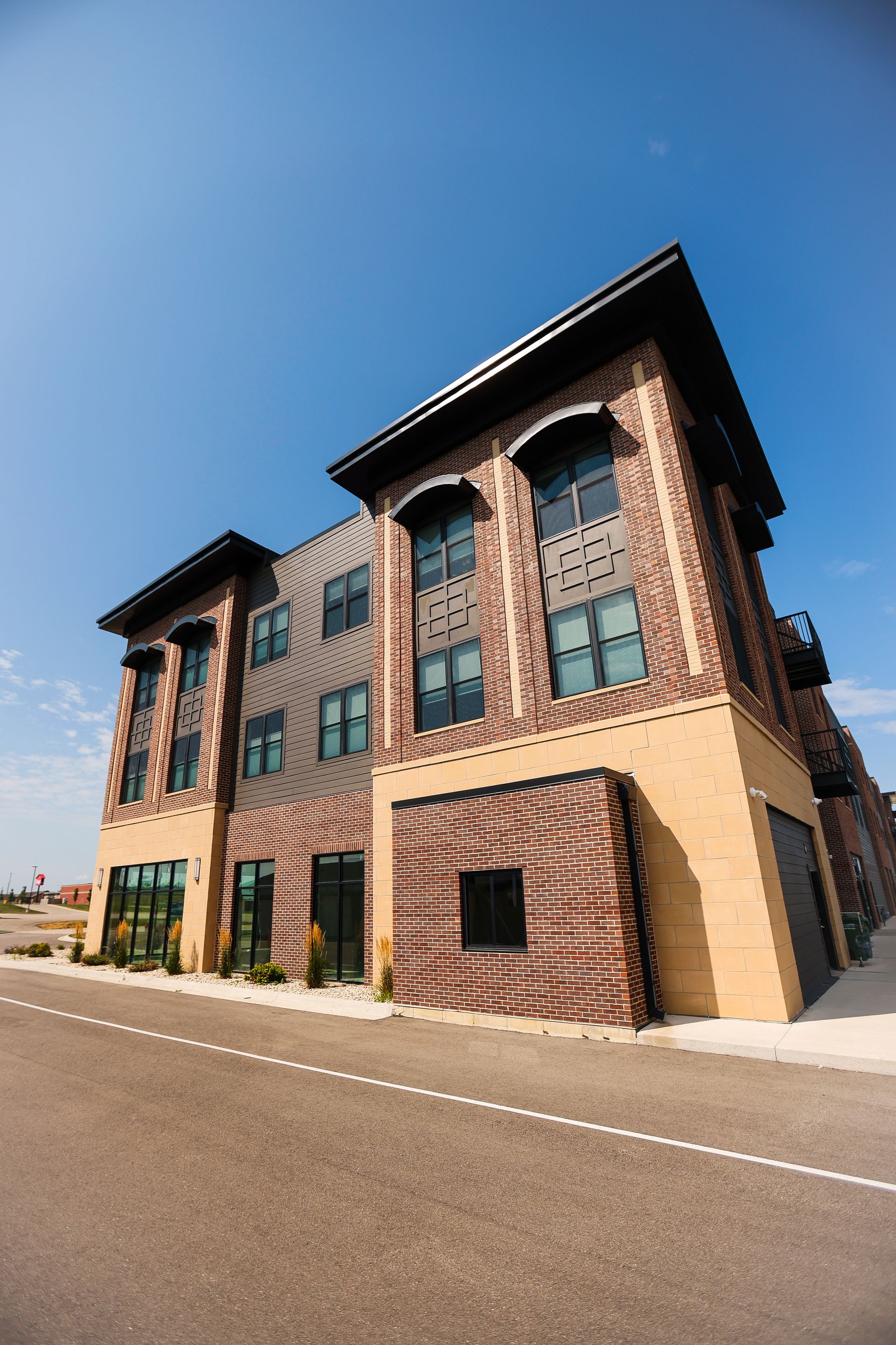 A large brick building with a lot of windows is sitting on the side of a road.