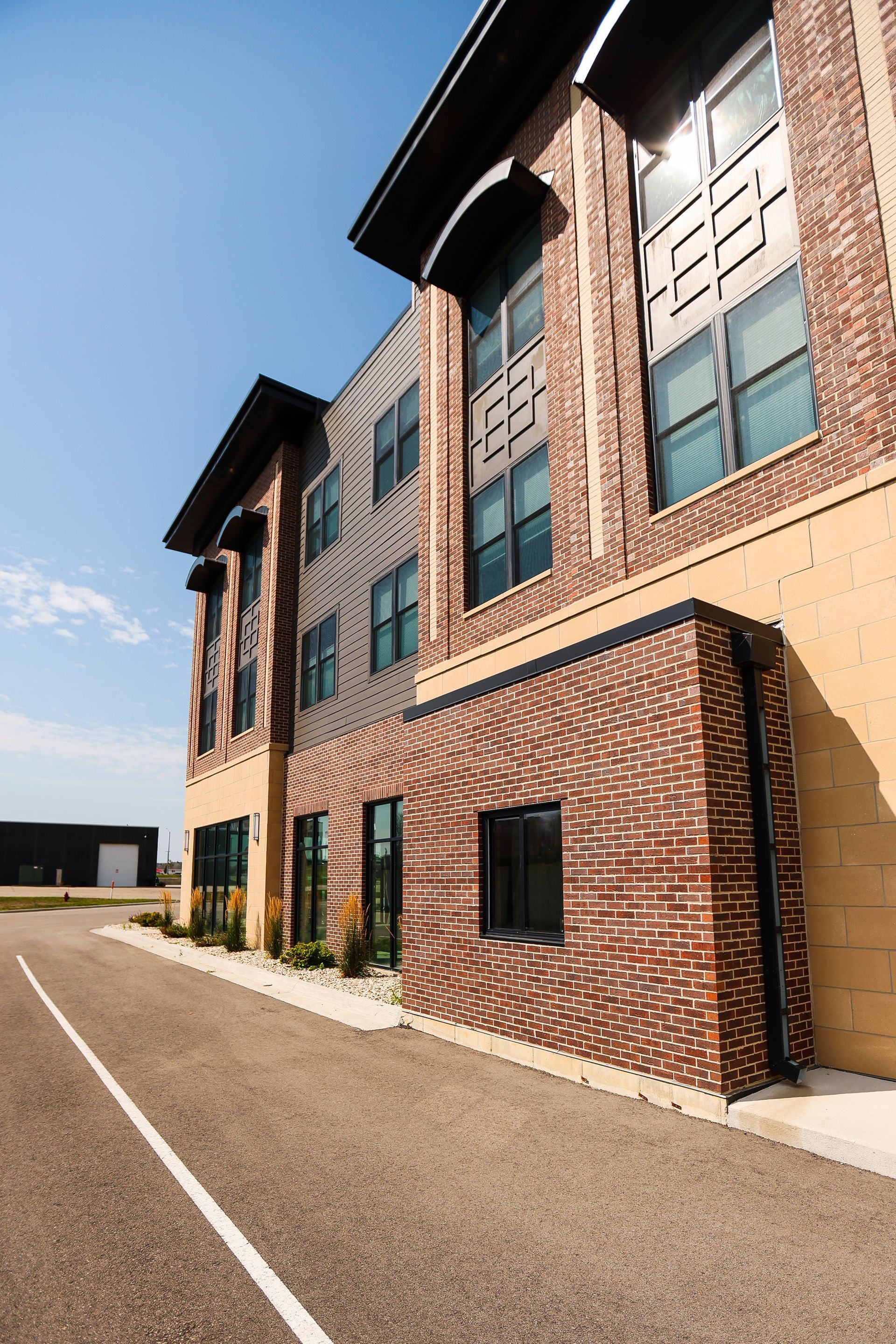 A large brick building with a lot of windows and a parking lot in front of it.