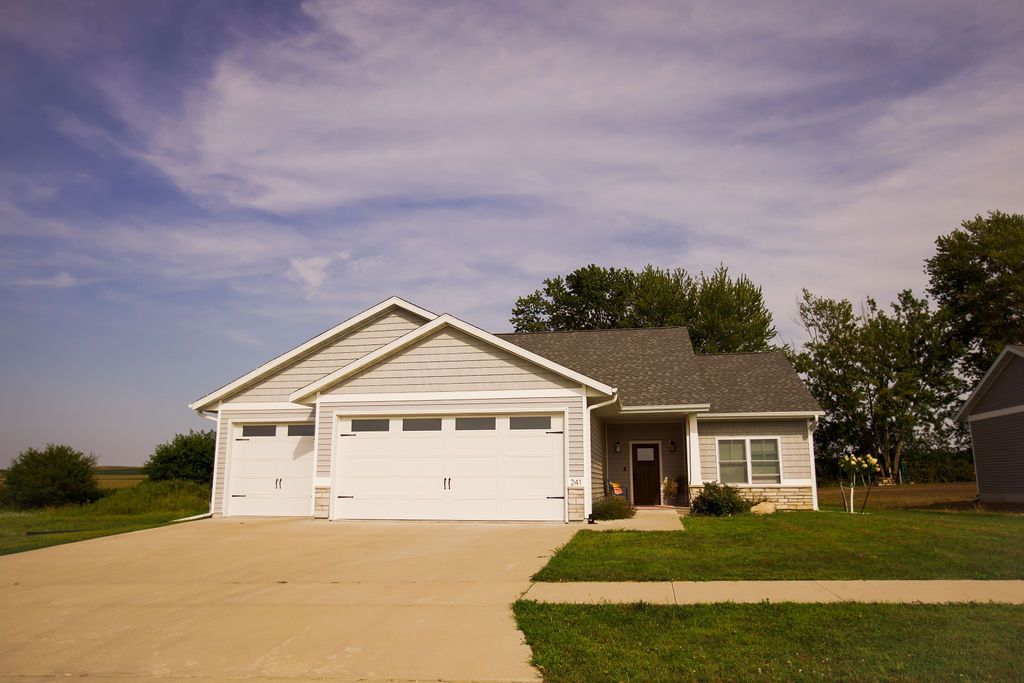 A white house with two garage doors and a concrete driveway