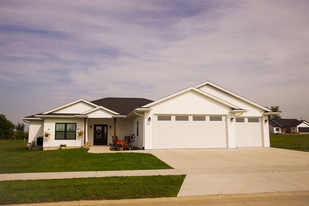 A large white house with a concrete driveway in front of it