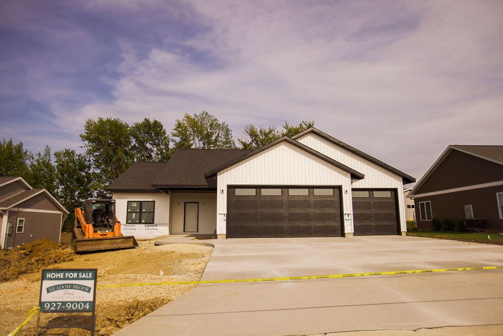 A house is being built in a residential area with a for sale sign in front of it.