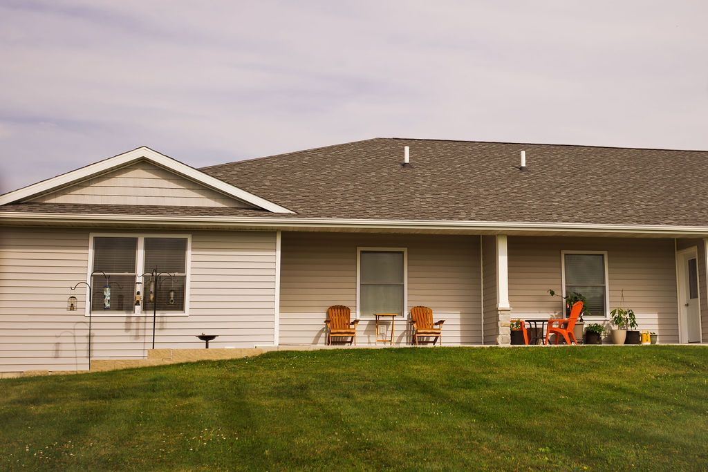 A house with a lawn and chairs in front of it.