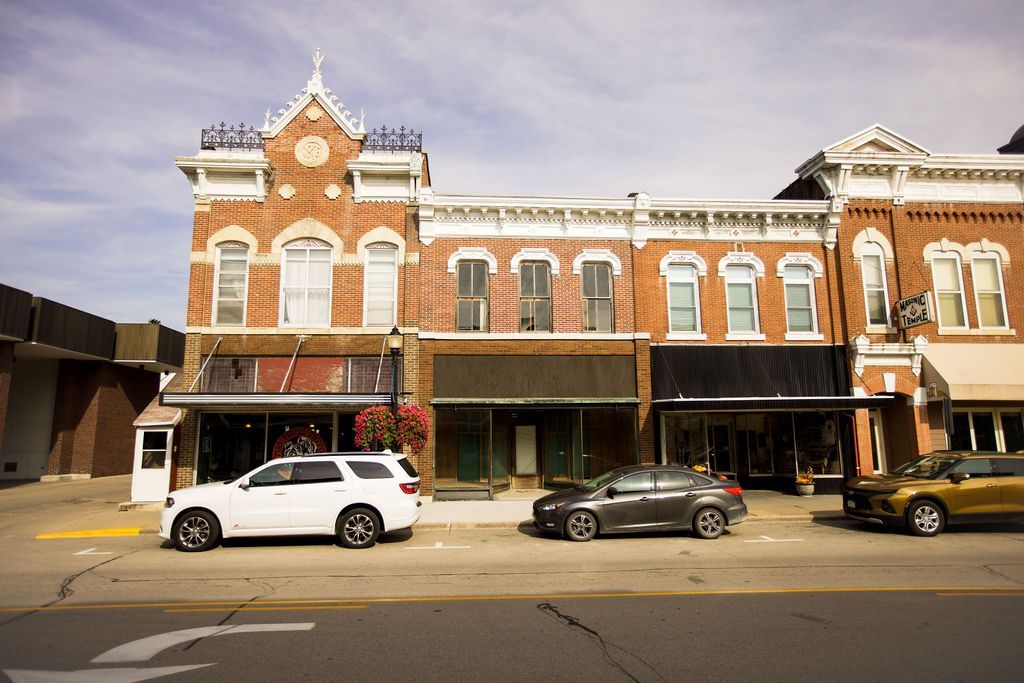 A row of brick buildings with cars parked in front of them