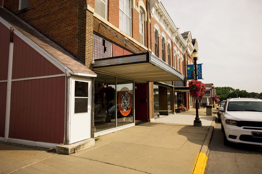 A white car is parked in front of a brick building.