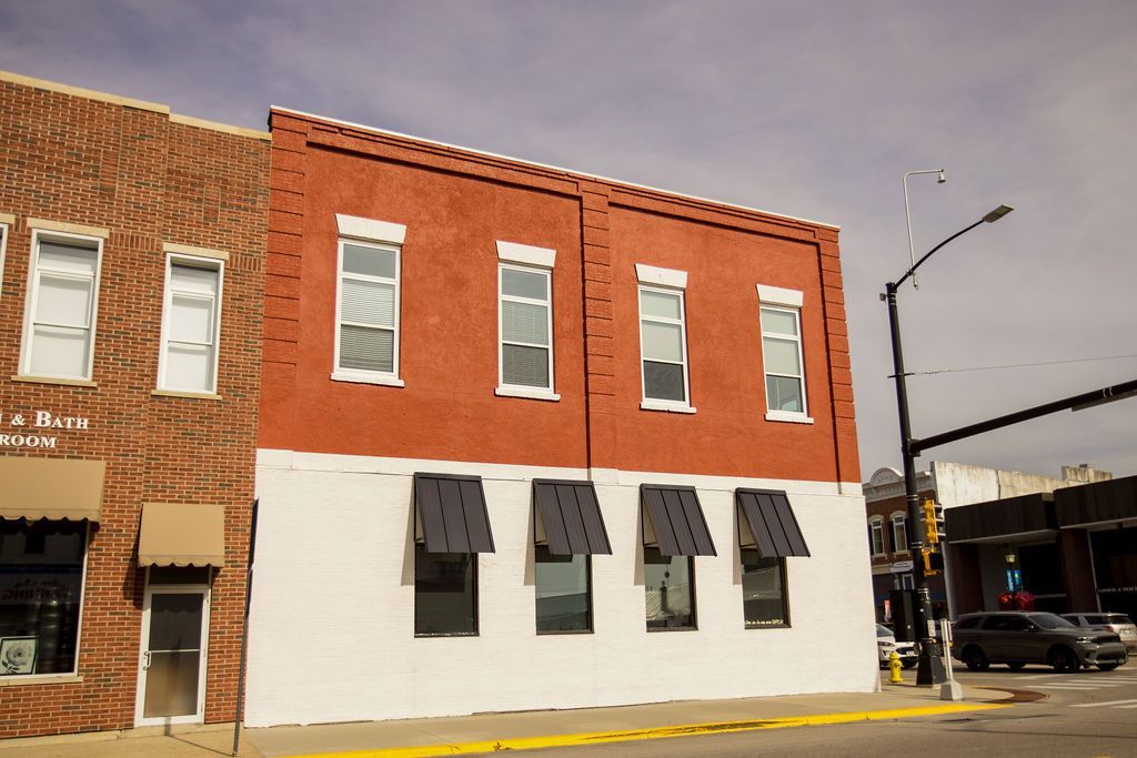 A red brick building with white trim and awnings on the windows