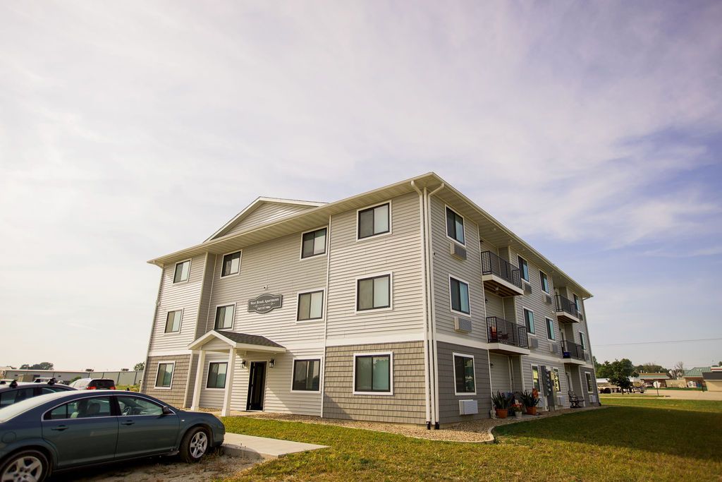 A large apartment building with cars parked in front of it.