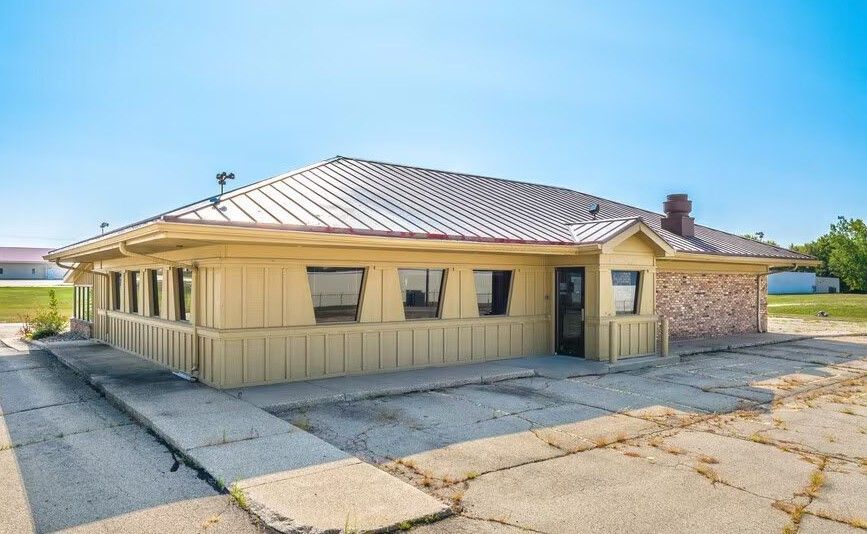 A small yellow house with a metal roof is sitting on the side of the road.