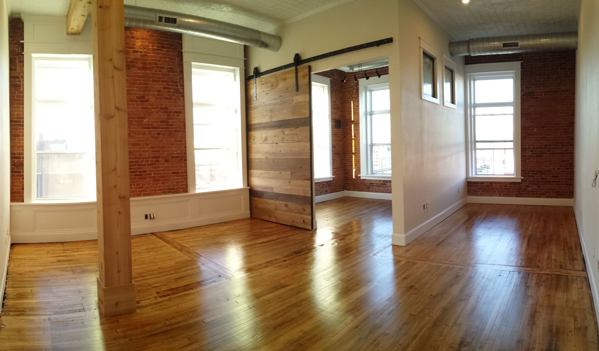 An empty room with hardwood floors and brick walls