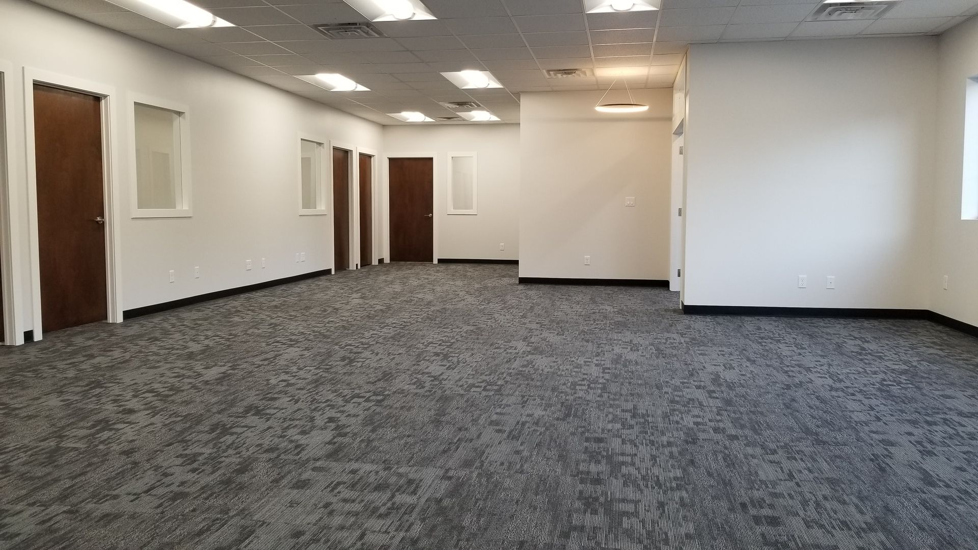 A large empty room with a carpeted floor and white walls.